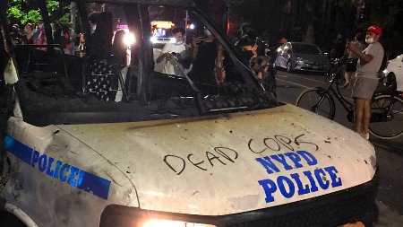 The remains of a scorched police vehicle lie vandalized during riots in the Fort Greene neighborhood in the Brooklyn borough of New York on May 29, 2020. - The woman who threw the molotov cocktail inside the vehicle occupied by four officers on the fringes of a demonstration in New York on Friday was arrested